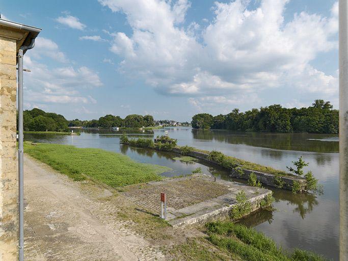 Le quai et le pertuis en maçonnerie de moellon devant le maison. En arrière-plan, la ville de Decize.