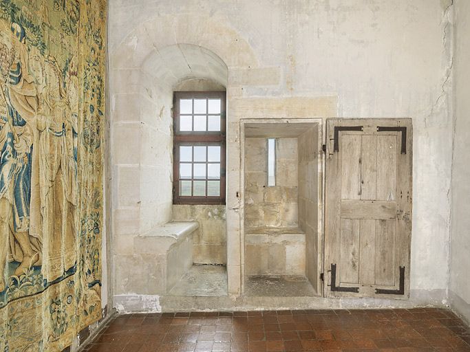 Appartement 15e siècle : pièce d'eau avec latrines et coussiège. Porte ouverte.