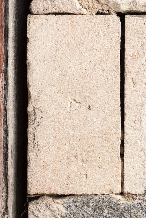 Marque de tâcheron sur la porte charretière à l'ouest de l'édifice.