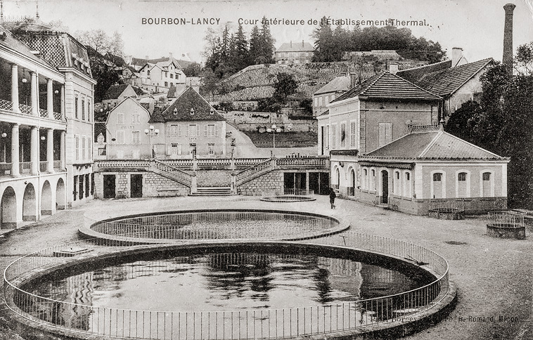 Vue ancienne de la cour de l'établissement thermal, avec la ville à l'arrière.