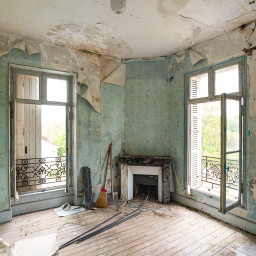 Chambre au premier étage avec deux fenêtres et une cheminée dans l'angle.