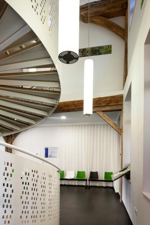 Bâtiment après reconversion : Pôle de santé libéral et ambulatoire (PSLA), escalier et poutres.