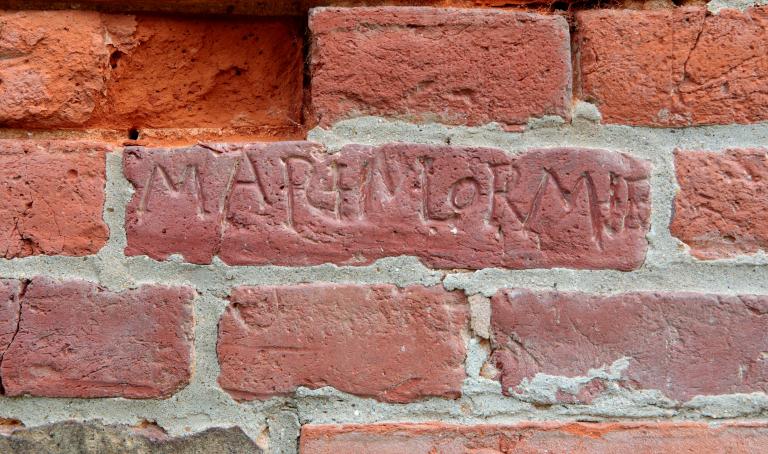 Pignon nord, détail d'une brique portant une inscription. 