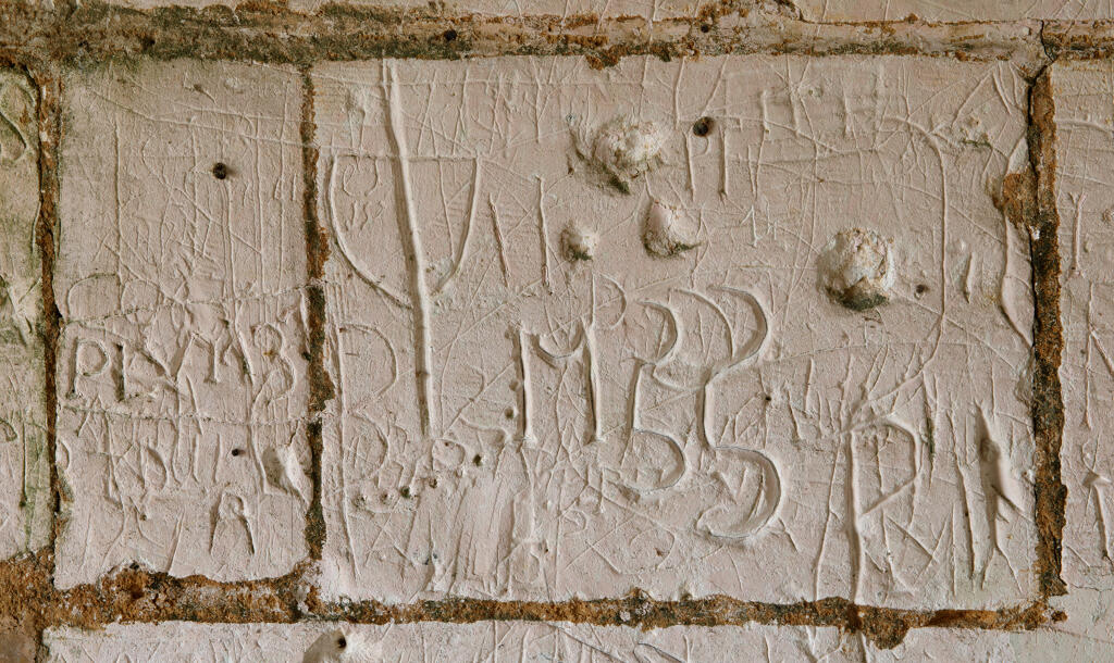 Graffiti gravés sur les murs extérieurs et sous le porche de l'église.