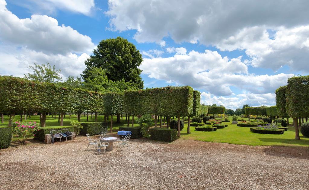 Bosquets et allées de tilleuls taillés à l'avant du château. 