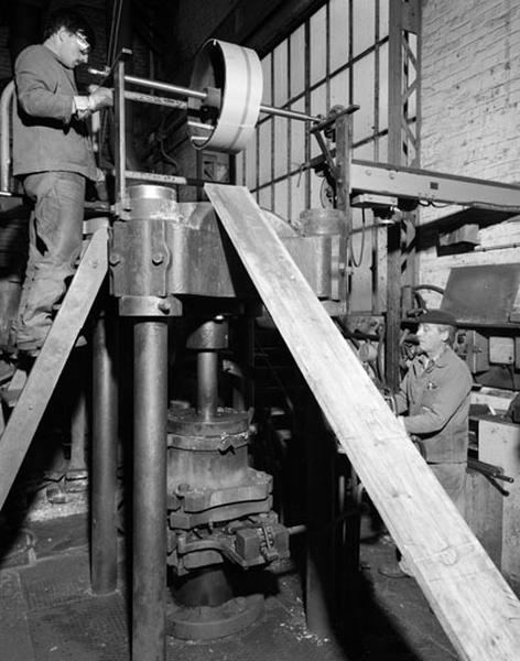 Machine en fonctionnement et ouvriers.