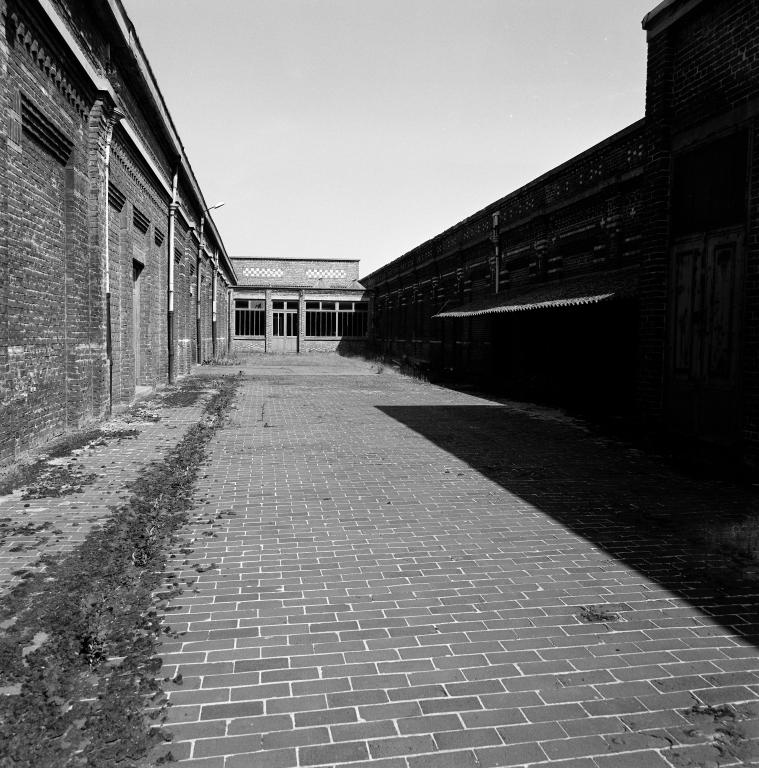Vue en enfilade prise vers le nord, entre les bureaux et le magasin aux toiles à gauche et le tissage à droite.