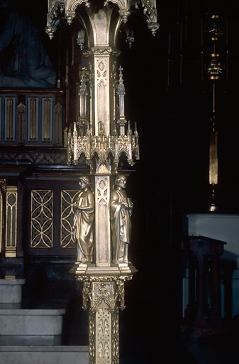 Vue de détail de la partie centrale d'un chandelier comprenant deux statuettes de saints.