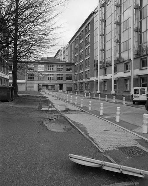 Vue en enfilade sur la cour qui s'étend au nord-ouest du bâtiment principal d'hospitalisation, montrant, sur la droite, la face postérieure de ce bâtiment avec les constructions en surépaisseur qui ont comblé les renfoncements préexistants.