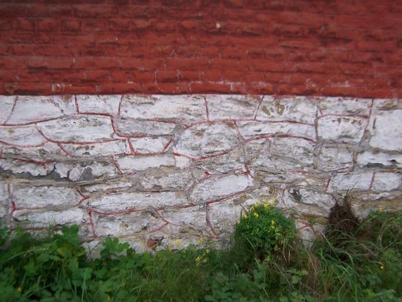 Détail du mur pignon sur rue : le soubassement en moellon de calcaire carbonifère (badigeonné de chaux).