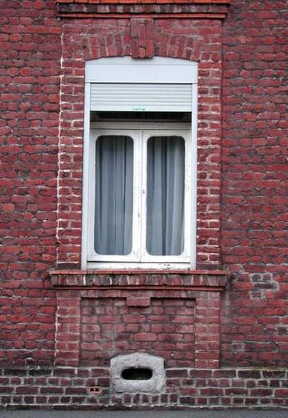 Rang nord-ouest : maison faisant l'angle avec la rue de la Bibliothèque, détail, rez-de-chaussée, fenêtre avec encadrement de reliefs de brique.