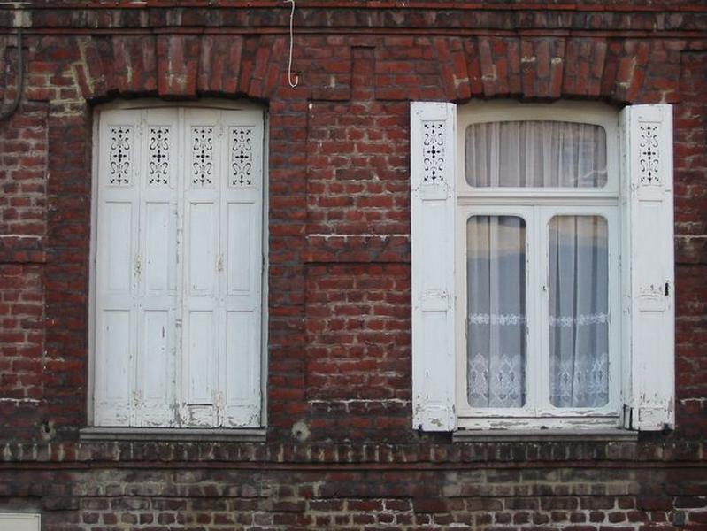 Rang nord-ouest : maison n° 31, détail, rez-de-chaussée, fenêtres garnies de volets en menuiserie ajourée.