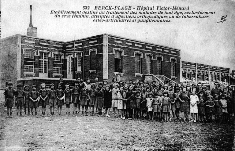 Elévation antérieure, tournée vers l'est, où sont aménagées les terrasses de cure, état avant l'agrandissement de l'aile gauche, vue générale prise de trois-quarts gauche montrant un groupe de filles pensionnaires au premier plan. Carte postale, années 1920. 