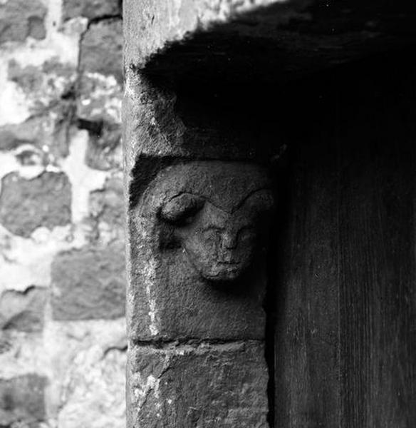 Corps de logis médiéval, façade arrière, tourelle d'escalier (ouest), rez-de-chaussée, porte d'accès, détail : tête féminine sculptée sur le coussinet portant le linteau.