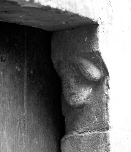 Corps de logis médiéval, façade arrière, tourelle d'escalier (ouest), rez-de-chaussée, porte d'accès, détail : tête masculine sculptée sur le coussinet portant le linteau.  