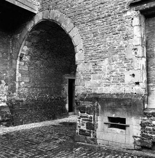 Corps de logis médiéval, façade arrière, rez-de-chaussée, vue partielle : débouché du passage couvert et, au premier plan, emplacement de l'accès d'origine à la cave.