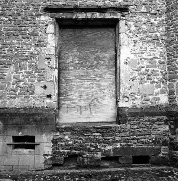 Corps de logis médiéval, façade arrière, rez-de-chaussée, vue partielle : baie occultée et accès condamné à la cave.