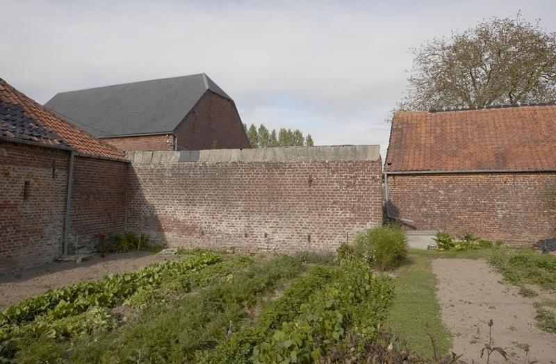 Vue du mur de clôture, d'une remise et du pignon de la grange.