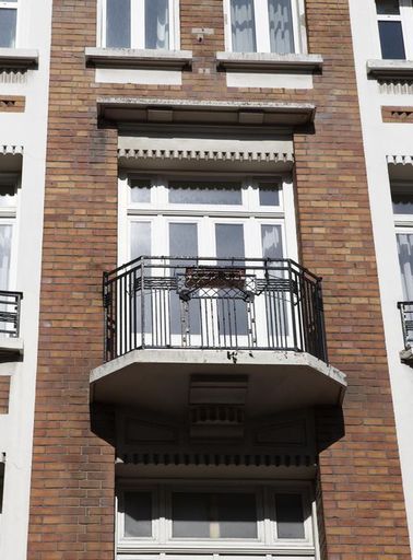 Baie centrale avec balcon et linteau aux formes géométriques.