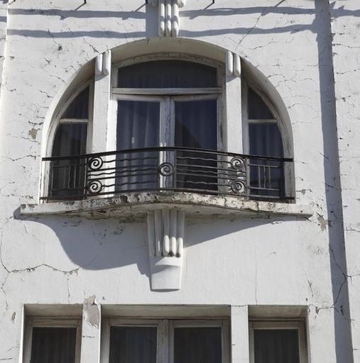 Baie cintrée ornée de motifs tubulaires et d'un garde-corps aux motifs en spirales et de vagues.