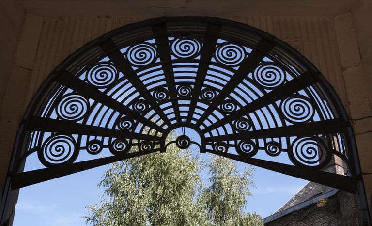 Vue de détail du couronnement de la porte cochère constitué de motifs en spirales.