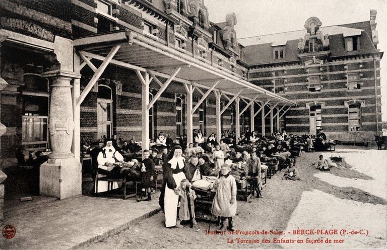 Bâtiment d'hospitalisation latéral sud, élévation antérieure donnant sur la plage, galerie de cure avec enfants allongés à l'ombre de la galerie, face à la mer. Carte postale, début du 20e siècle  (coll. part.).