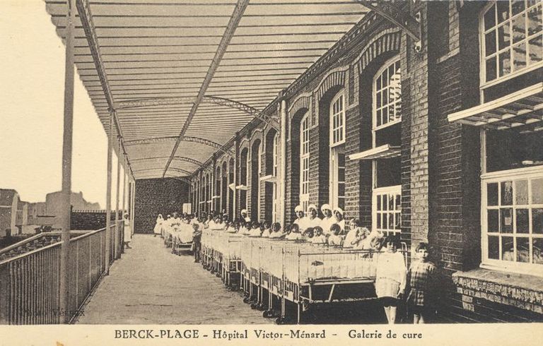 Elévation antérieure, terrasse de cure couverte d'un auvent, vue en enfilade montrant de jeunes enfants installés à l'abri de cette galerie chacun dans leur lit. Carte postale, années 1920-1930.