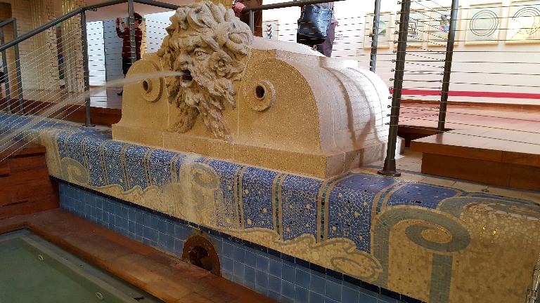 Tête grotesque dite « le lion » servant de fontaine au bassin de la piscine de Roubaix et détail de la mosaïque formant des vagues stylisées de la margelle du bassin.