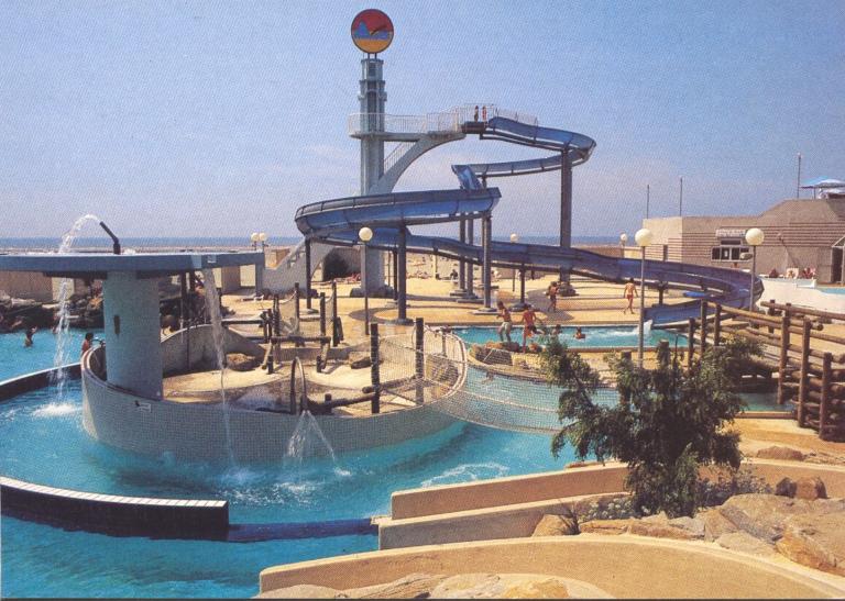 Toboggans et zones de jeux aquatiques extérieurs à l’Aqualud du Touquet-Paris-Plage. La tour marquant le départ du toboggan est le plongeoir de l’ancienne piscine. Carte postale, vers 1985 (coll. part.).
