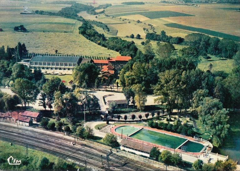 Vue aérienne du centre de vacances de la S.N.C.F. à Montdidier, à proximité de la voie de chemin de fer : auberges de jeunesse, installations de loisir et sportives (piscine, etc.), carte postale, [vers 1970] (coll. part.).