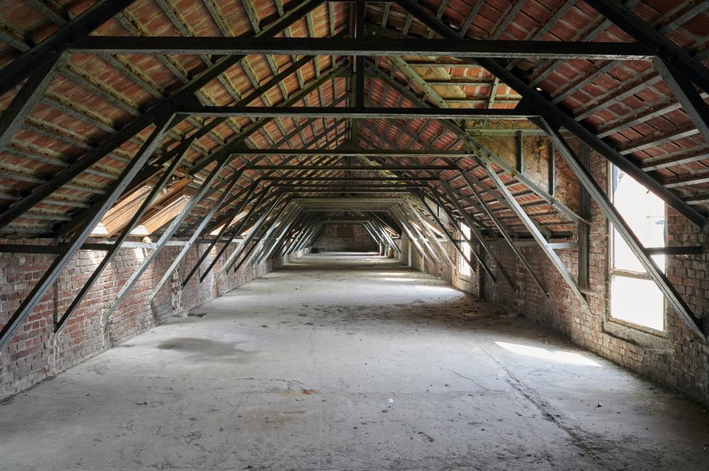 Combles des anciennes grandes étables avec sa charpente métallique apparente.