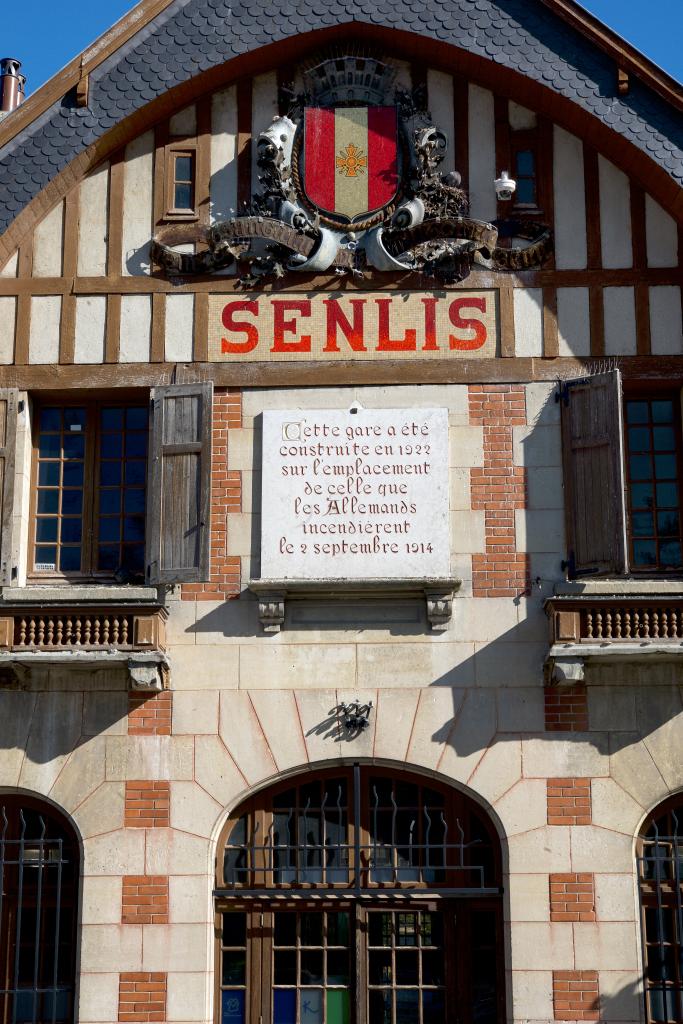 Détail du fronton de la gare portant les armes de la ville de Senlis et l'inscription rappelant les circonstances et la date de la reconstruction.
