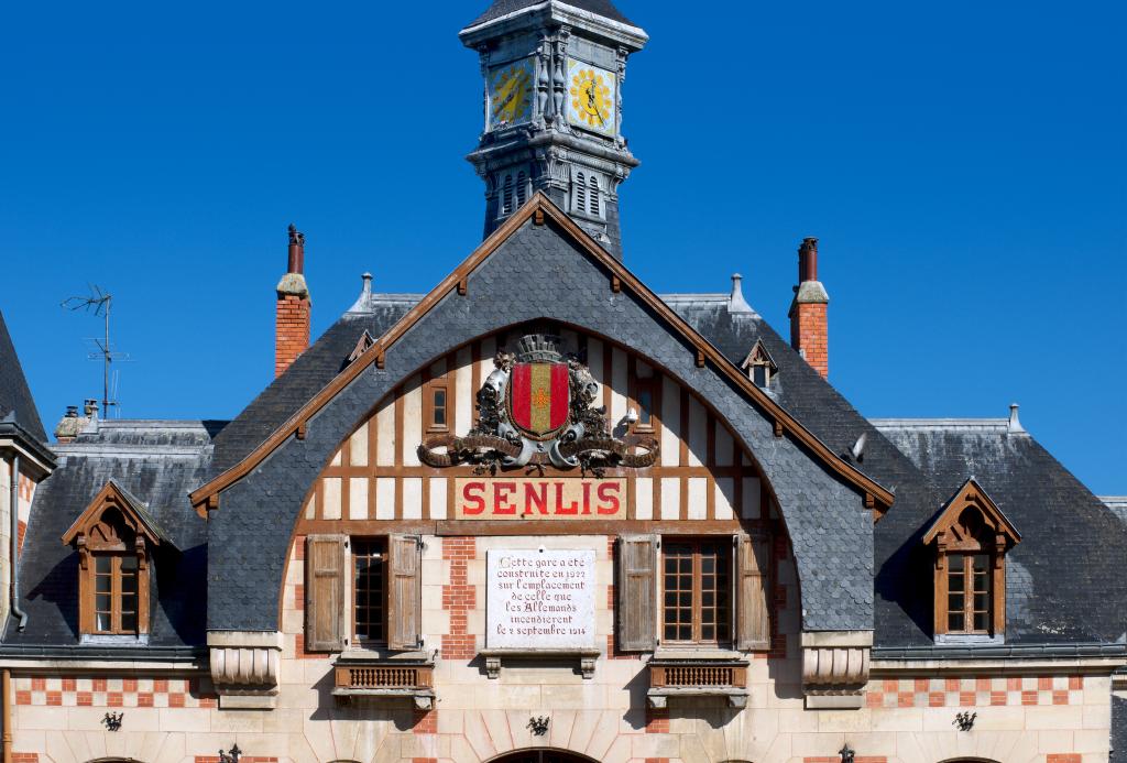 Détail du fronton de la gare portant les armes de la ville de Senlis et l'inscription rappelant les circonstances et la date de la reconstruction.
