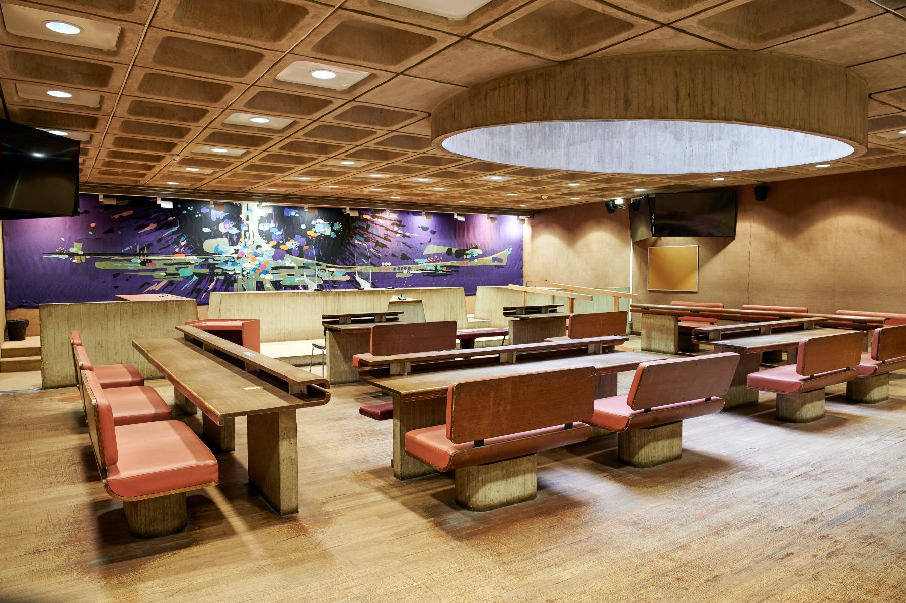 Ancienne petite salle d’audience du tribunal d’instance du rez-de-chaussée bas, vue de trois quarts. Derrière l’estrade des juges, la tapisserie de Michel Degand, « D’étoiles dans les soirs tremblants ».