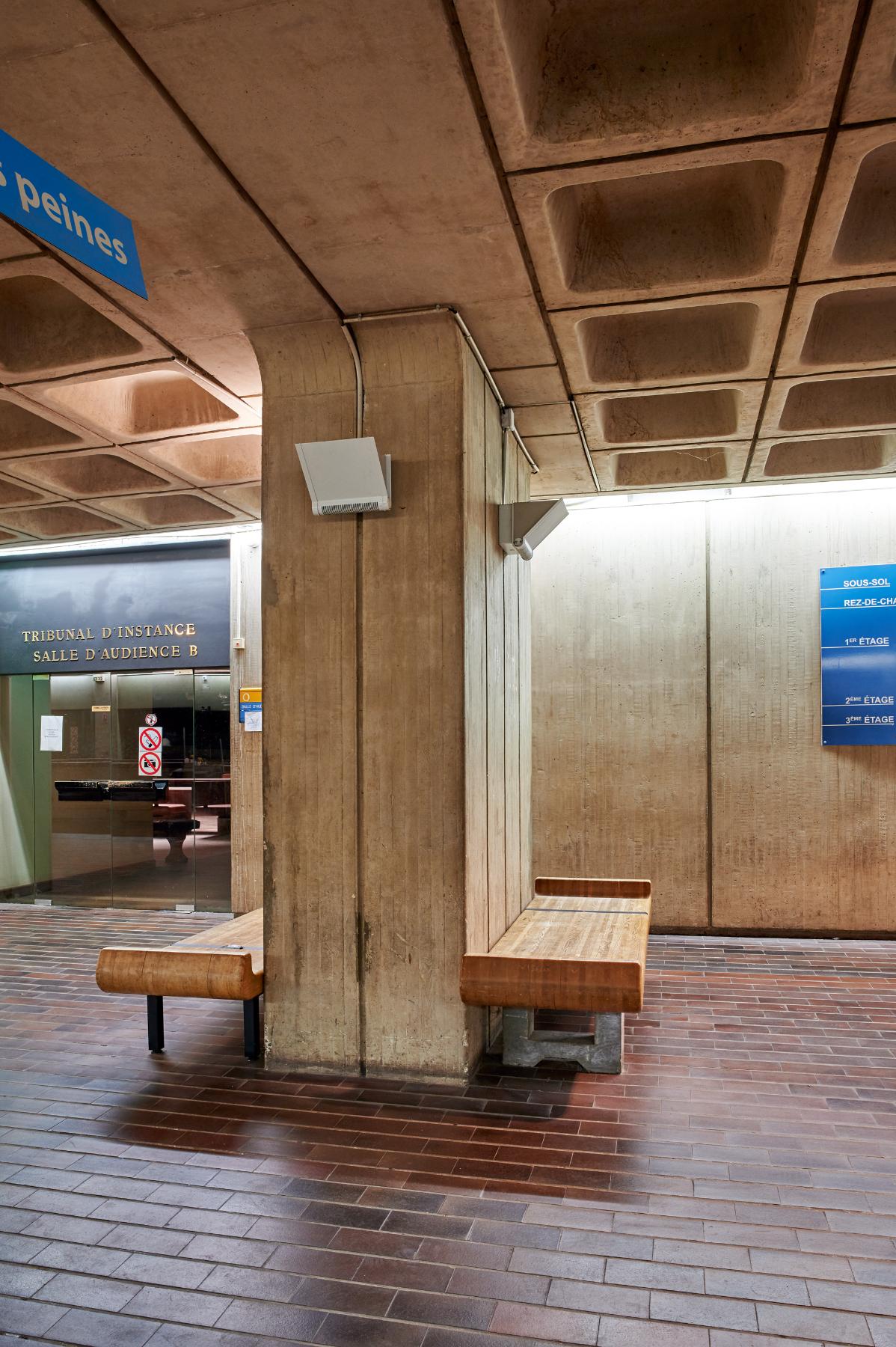 Bancs dos-à-dos avec pilier en béton servant de dossier.