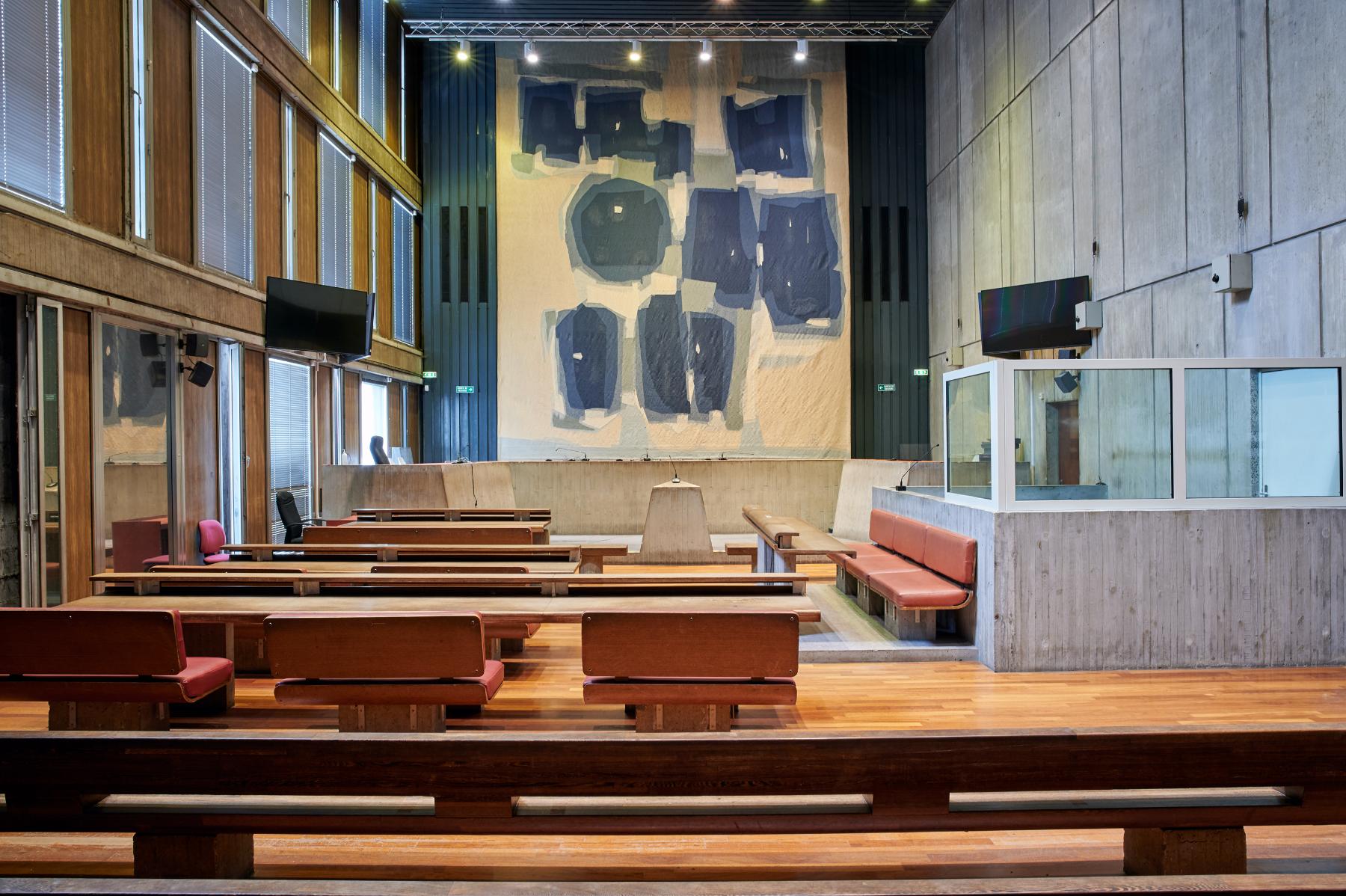 Une salle d’audience du rez-de-chaussée haut accessible par la salle des pas perdus. Le mur du fond est orné d’une tapisserie de Raoul Ubac.