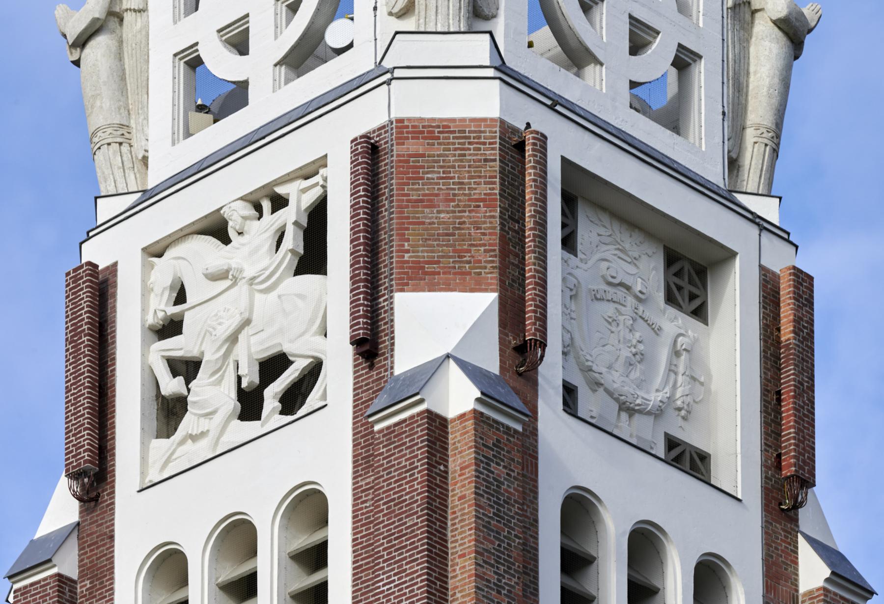 Vue de détail des panneaux sculptés du clocher-porche représentant la Charité de Saint-Martin et les armes de la commune réalisés par Marcel Bouraine.
