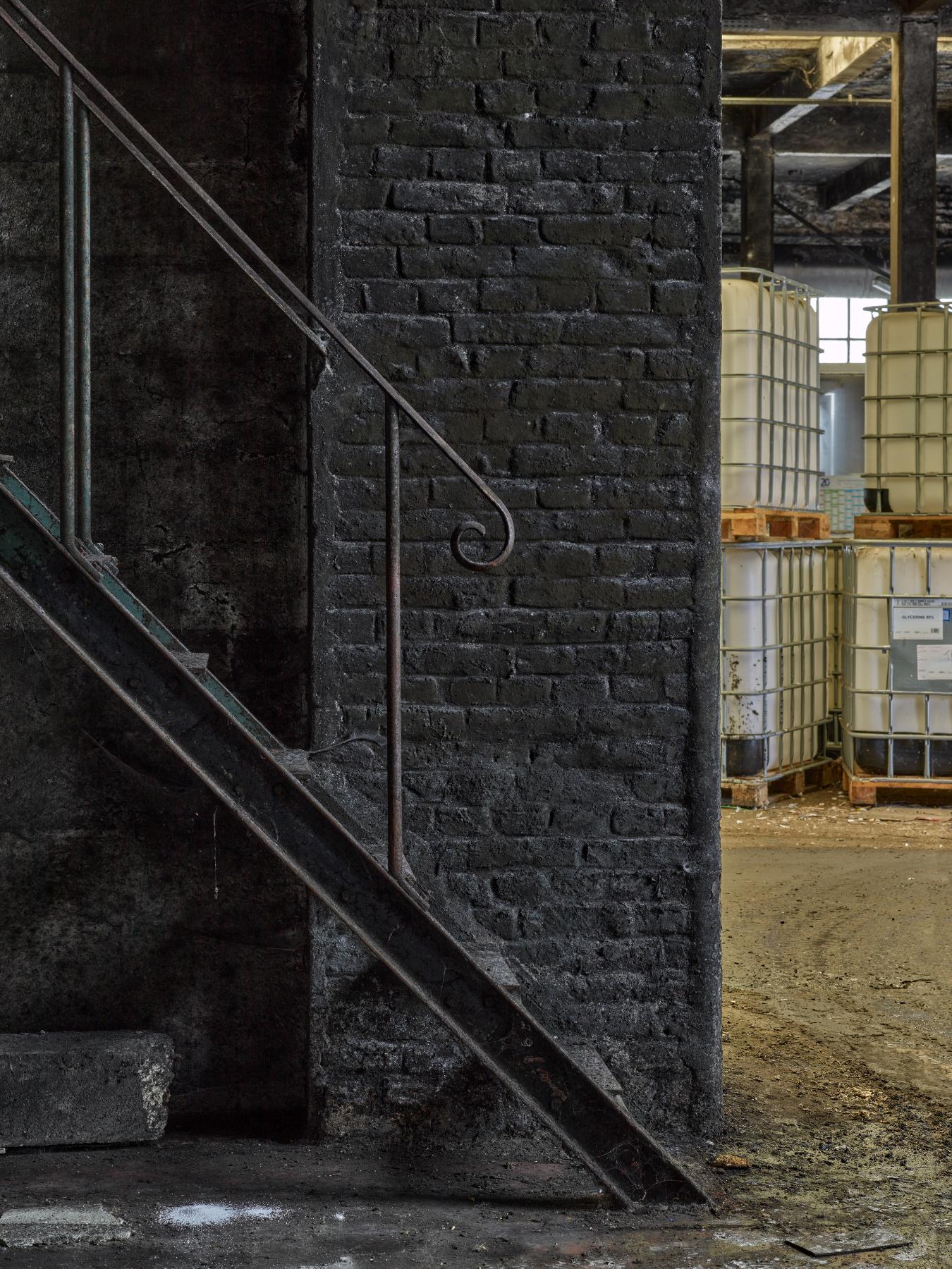 Rez-de-chaussée de l'atelier de fabrication (bâtiment K), détail de l'escalier métallique menant au bureau du contremaître.