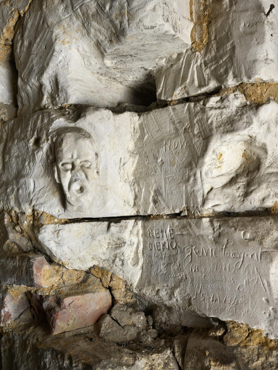 Tête d'homme et inscription gravée sur les murs intérieurs de la prison du beffroi.