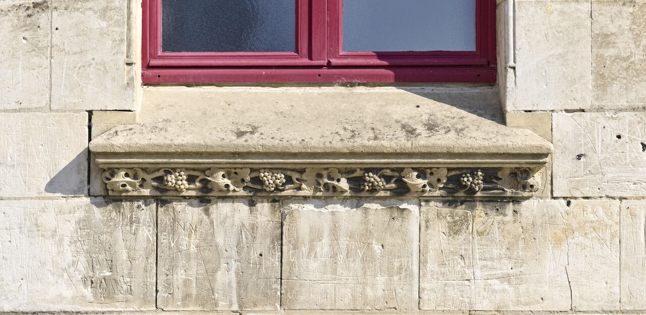 Détail du décor de ceps de vigne et de raisin en appui de fenêtre de la façade ouest du beffroi.