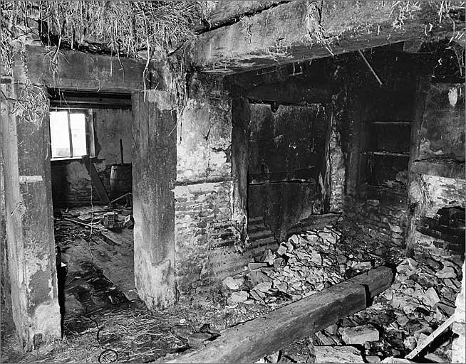 Logis gauche, cuisine, cheminée au large et four à pain et porte d'accès à la pièce de devant.