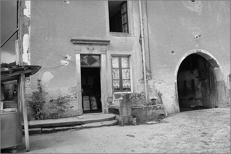 Ferme, élévation antérieure, détail : porte piétonne et banc, ensemble trois quarts gauche.