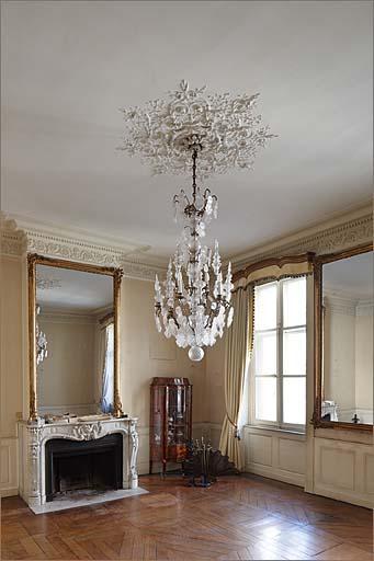 Cheminée avec glace de trumeau, parquet d'assemblage et décor de plafond.