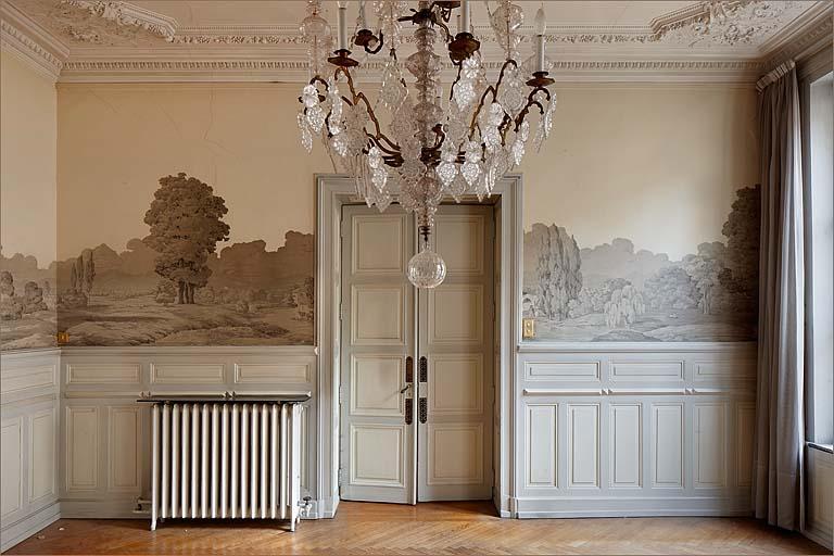 Mur vers couloir d'entrée, lambris d'appui et papier peint panoramique.