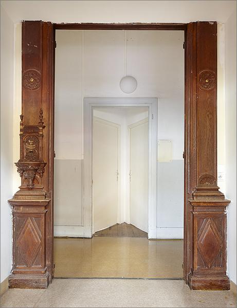Détail d'une porte latérale (côté couloir, face intérieure) avec un ancien tronc (à gauche).