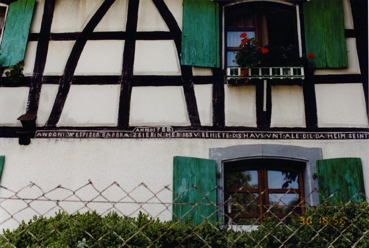 Vue de détail de l'inscription située sur le pignon sur rue du logis.