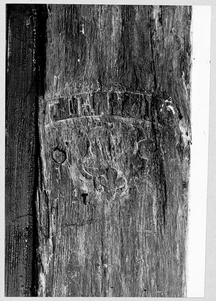 Mur ouest, détail du pan de bois à l'intérieur : blason en relief et banderole portant une inscription.