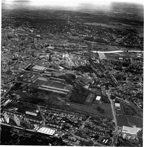 Vue aérienne de Dornach vu du nord-est, au premier plan quartier du Brustlein, au centre l'usine D.M.C, à gauche la ville de Mulhouse.