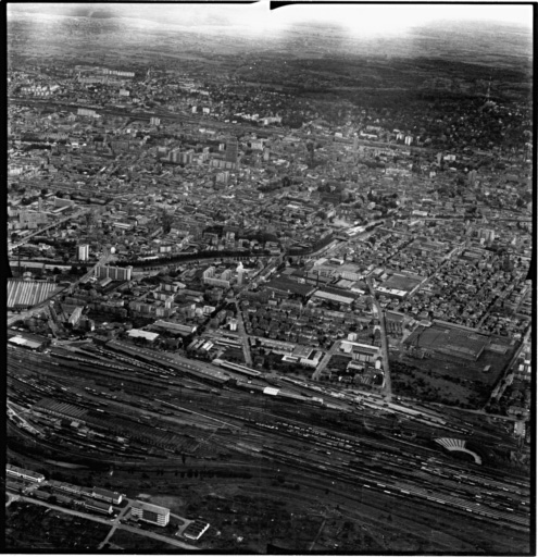 Vue aérienne : la ville vue du nord. A droite : la filature peignée Gluck, la gare du nord au premier plan, le centre ville derrière le canal de dérivation.