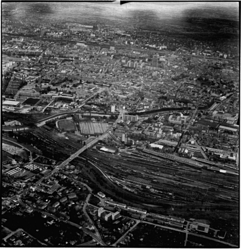 Vue aérienne : la ville vue du nord. A gauche au premier plan : Bourtzwiller, après le pont sur le chemin de fer, le musée de l'Automobile ; le centre ville derrière le canal de dérivation.